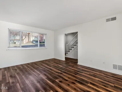 a view of an empty room with wooden floor and window