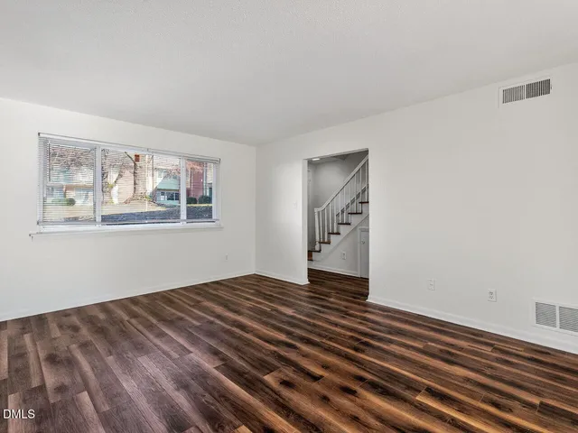 a view of an empty room with wooden floor and window