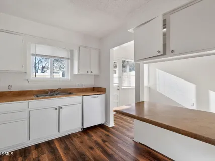 a large kitchen with cabinets wooden floor and a sink