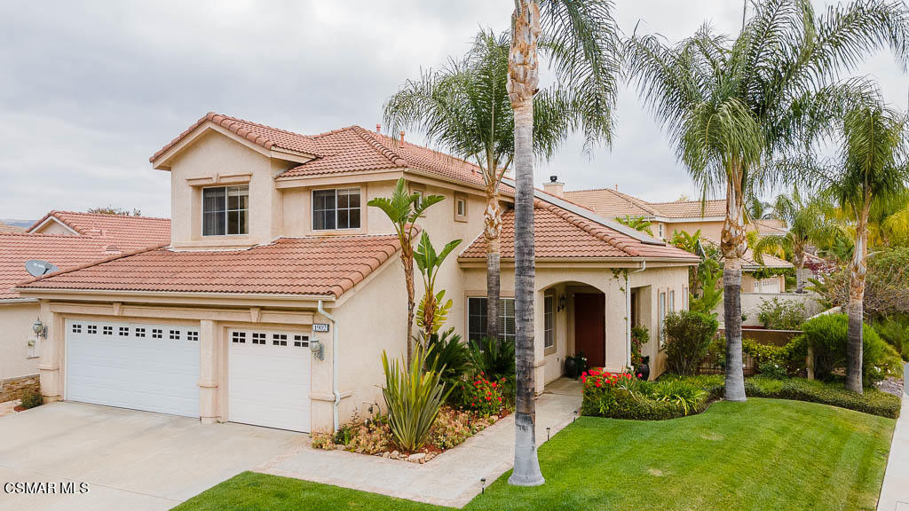 a front view of a house with a garden and palm trees