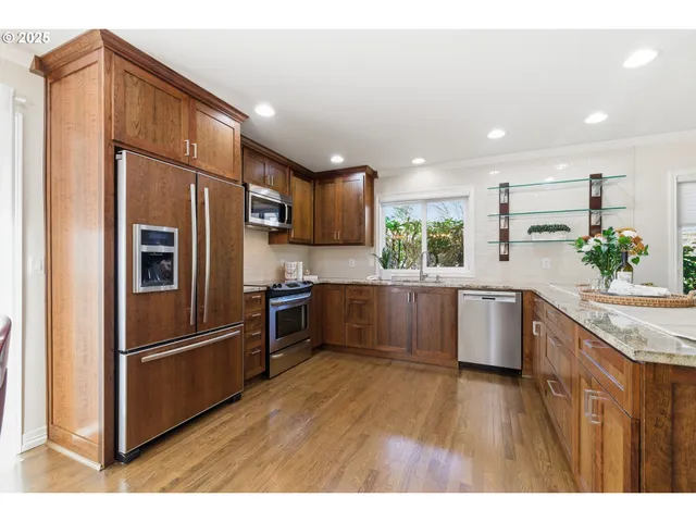 a kitchen with stainless steel appliances granite countertop a refrigerator a sink dishwasher a stove with wooden floors