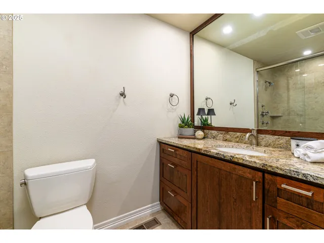 a bathroom with a granite countertop toilet sink and mirror