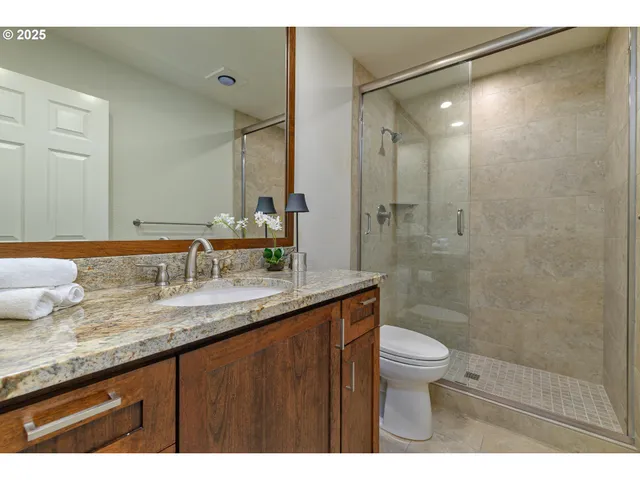 a bathroom with a granite countertop sink a toilet a mirror and shower