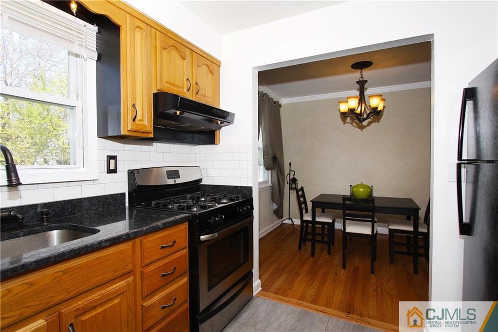 14 Wilshire Road Edison, NJ 08817 - Photo 9 of 22 a kitchen with granite countertop a stove a sink a dining table and chairs with wooden floor
