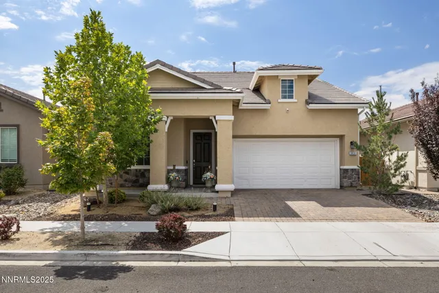 a front view of a house with garage and plants