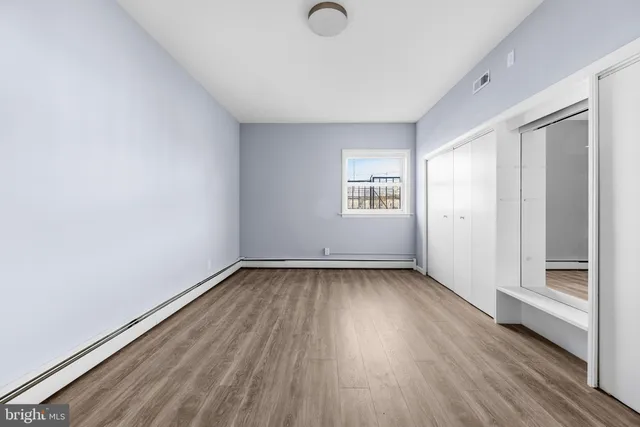 an empty room with wooden floor and windows