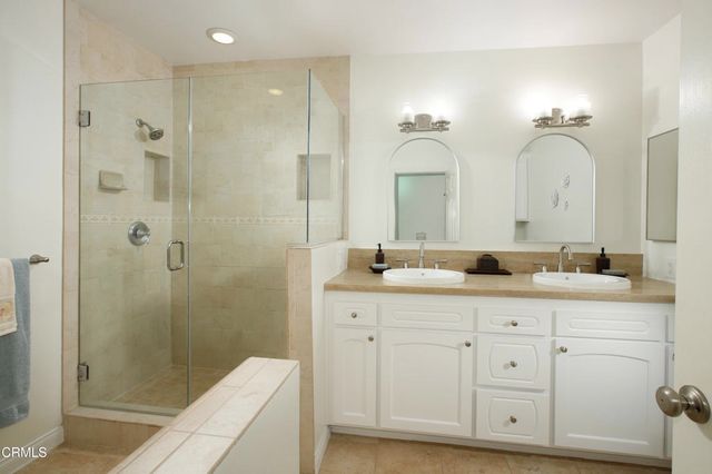 a bathroom with a double vanity sink mirror and shower