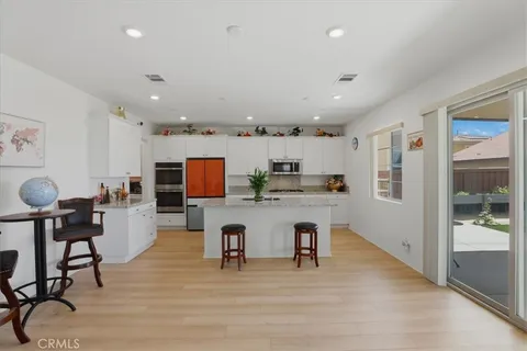 a living room with stainless steel appliances furniture and a kitchen view