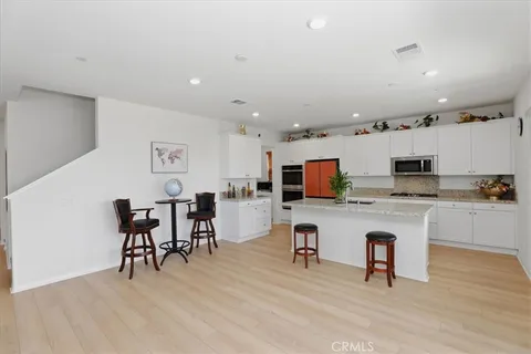 a living room with stainless steel appliances furniture and a flat screen tv