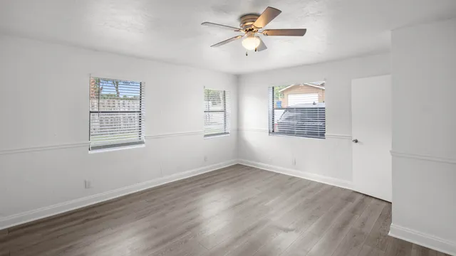 a view of an empty room with a window and wooden floor