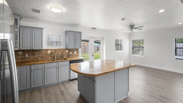 a kitchen with granite countertop a sink cabinets and wooden floor