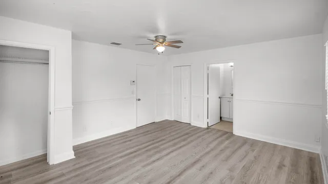 an empty room with wooden floor and fan