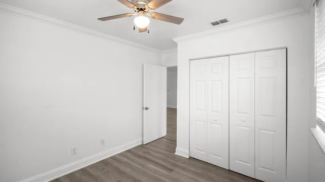 an empty room with wooden floor closet and fan