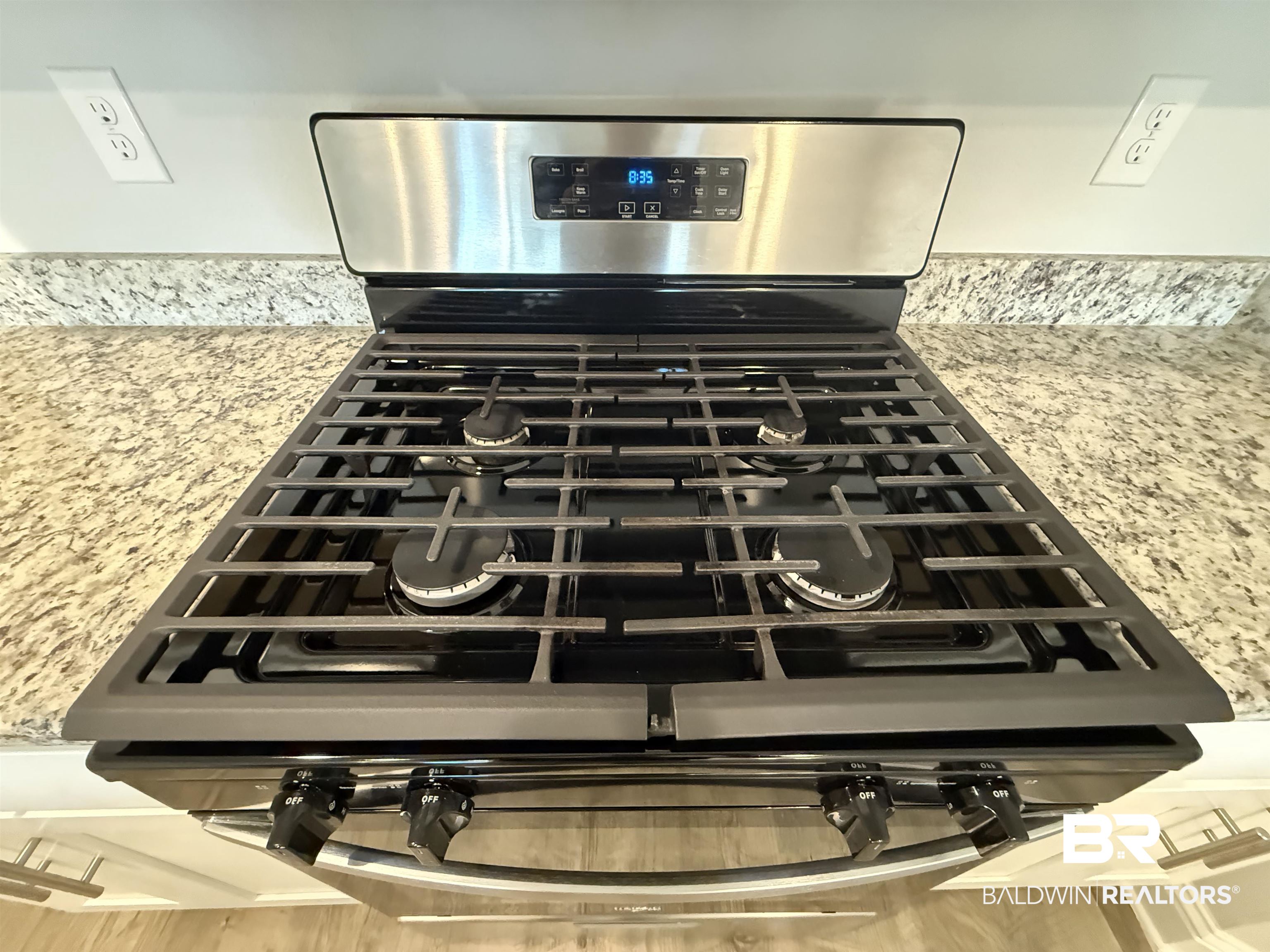 23247 Lieutenant Avenue Foley, AL 36535 - Photo 19 of 47 Stainless steel range with a gas cooktop, digital display, and four burners, complemented by a light-toned, speckled countertop