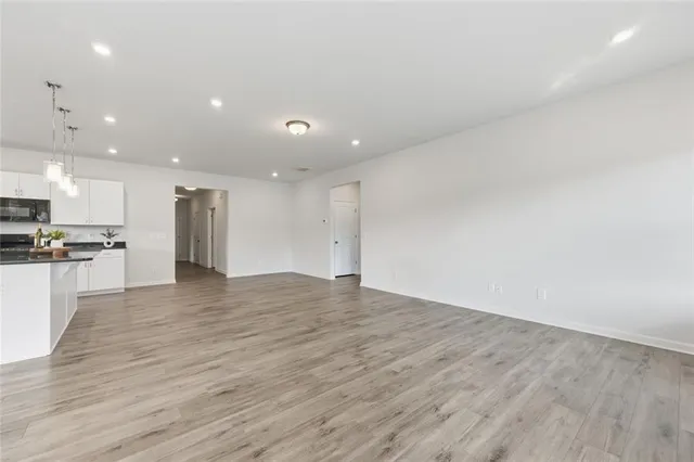 a view of kitchen with kitchen island a sink wooden floor and stainless steel appliances
