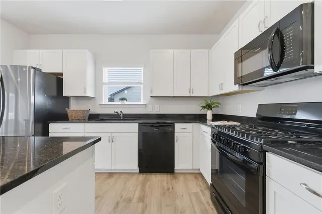 a kitchen with granite countertop a stove sink and refrigerator