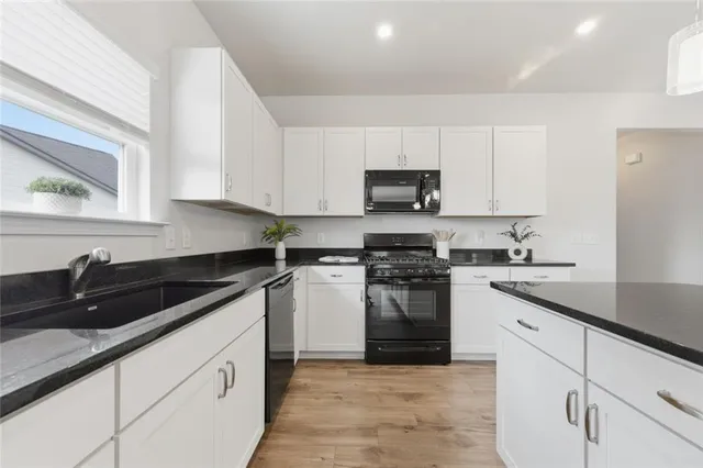a kitchen with granite countertop white cabinets and stainless steel appliances