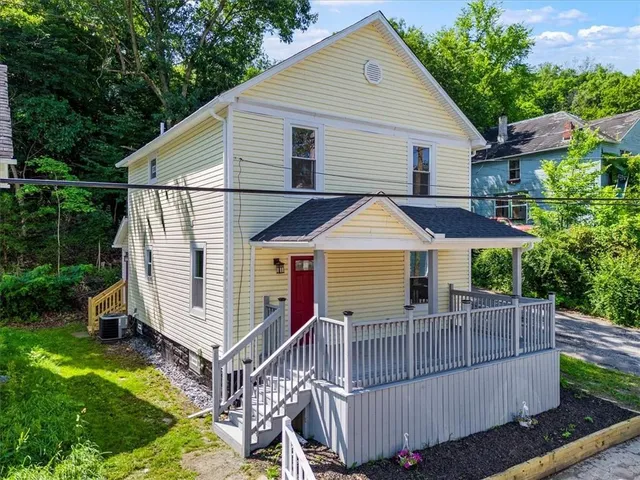 a view of a house with wooden deck and a yard with furniture