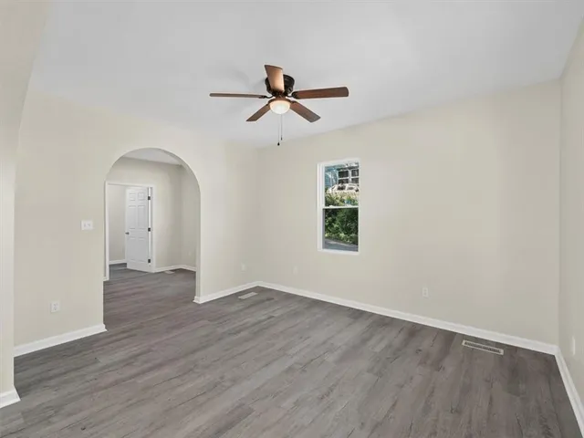 an empty room with wooden floor a ceiling fan and windows