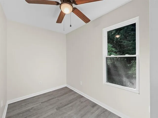 an empty room with wooden floor fan and windows