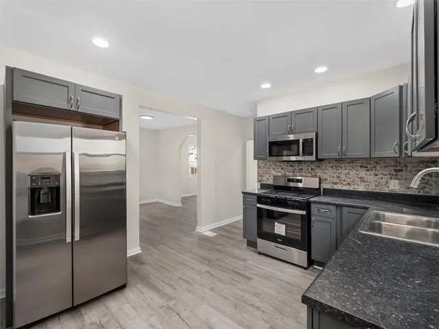 a kitchen with stainless steel appliances granite countertop a refrigerator a stove and a sink