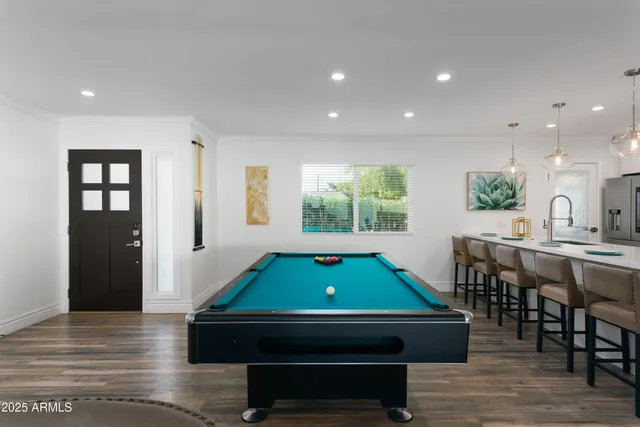 a room with furniture pool table wooden floor and windows
