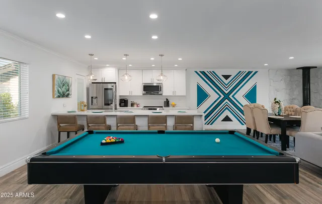 a room with wooden floor pool table and windows