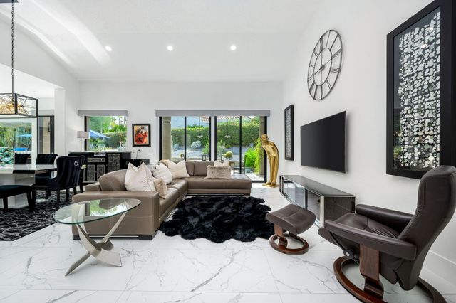 a living room with furniture a flat screen tv and a large window