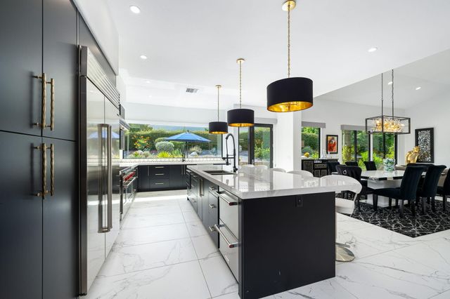 a kitchen with stainless steel appliances kitchen island granite countertop a sink a counter and chairs