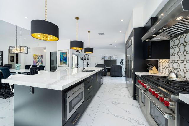 a kitchen with stainless steel appliances a stove a chimney a dining table and a sink