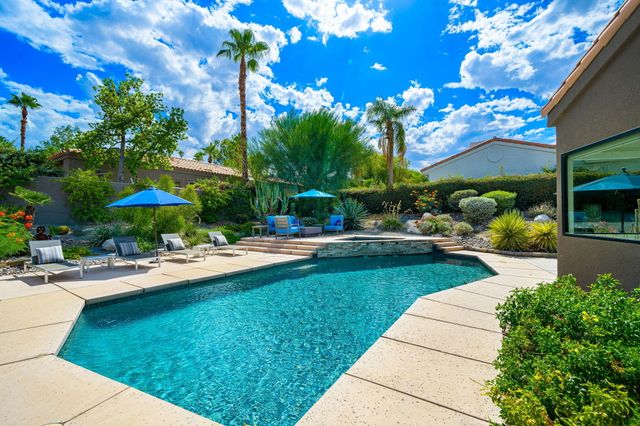 a view of a swimming pool with a table and chairs under an umbrella