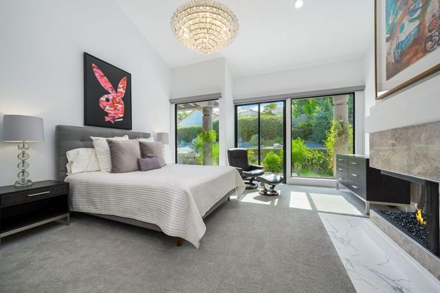 a spacious bedroom with a bed a chandelier and a fireplace