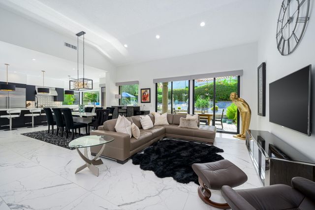 a living room with furniture a flat screen tv and a floor to ceiling window