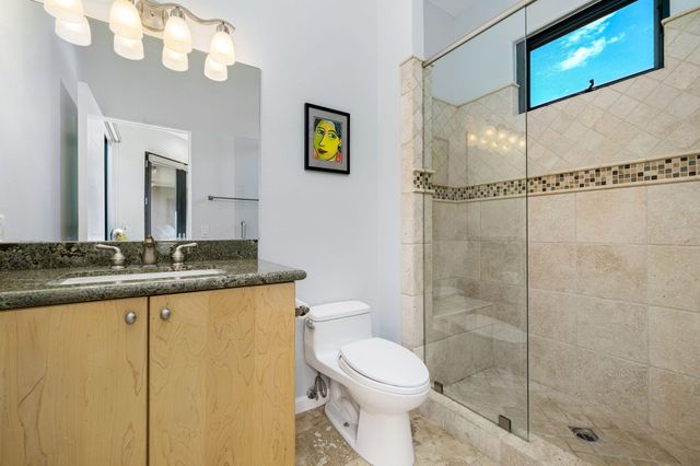 a bathroom with a granite countertop sink mirror vanity and toilet