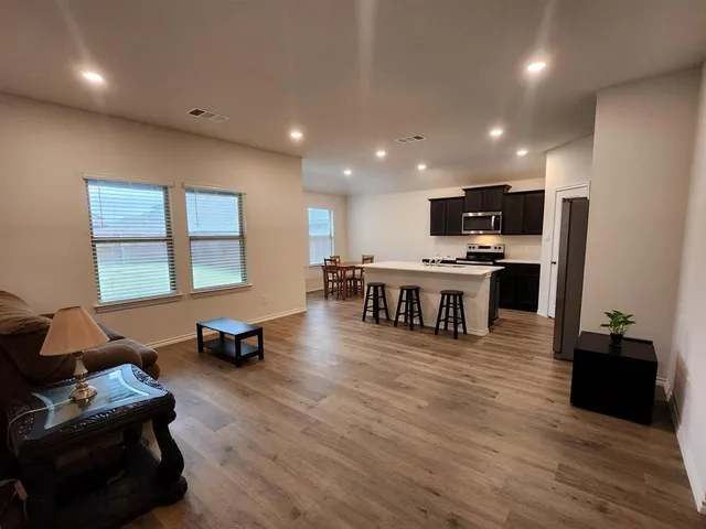 a living room with stainless steel appliances furniture and a wooden floor