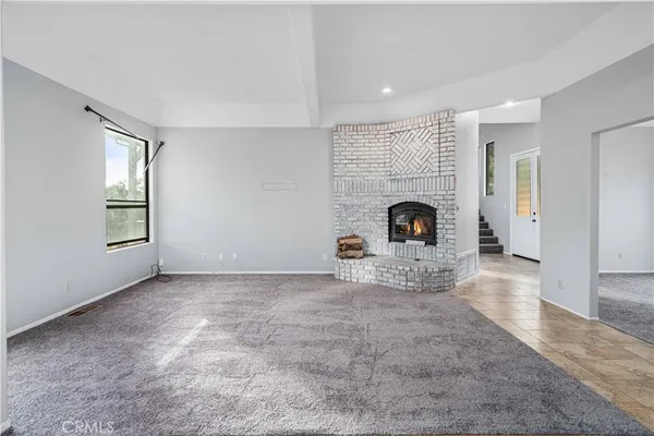 an empty room with windows and fireplace