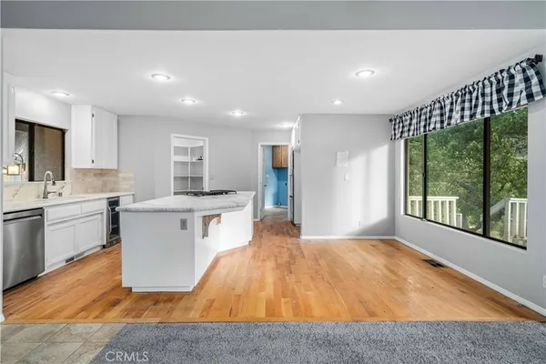 a open kitchen with white cabinets a sink dishwasher and a stove with wooden floor