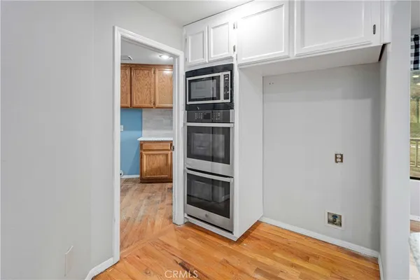 a view of an empty room with kitchen and window