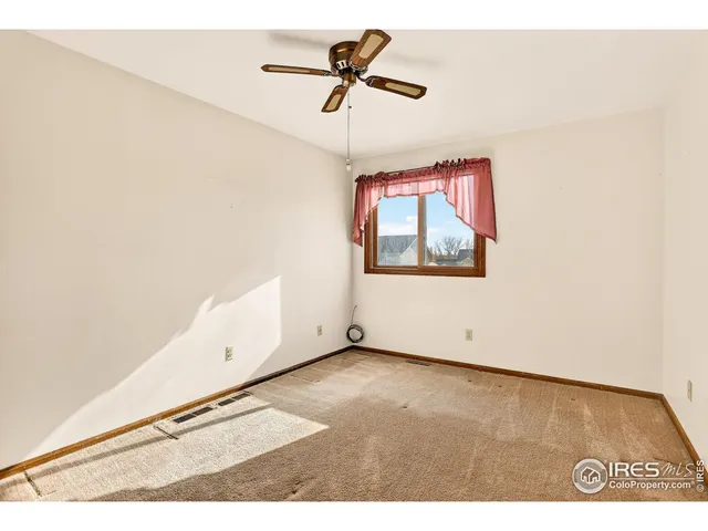 an empty room with a window and a ceiling fan