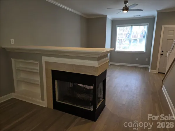 a living room with a fireplace a window and wooden floor