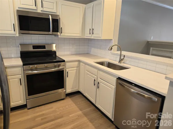 a kitchen with stainless steel appliances granite countertop a stove microwave and sink