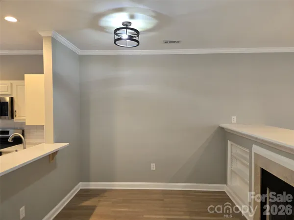 a view of an empty room with a fireplace and wooden floor