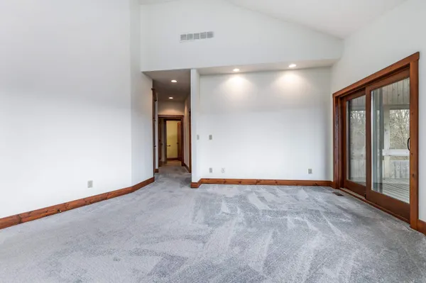 a view of an empty room with wooden floor and window