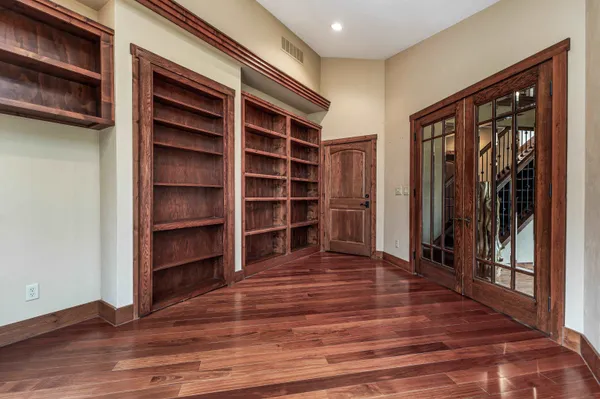 an empty room with wooden floor closet and windows