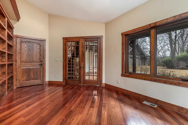 a view of an empty room with wooden floor and a window