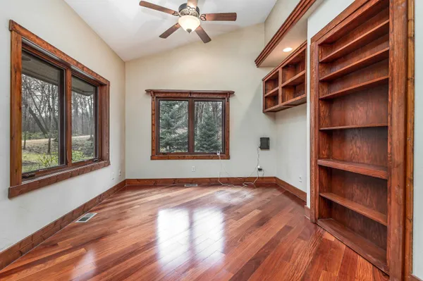 an empty room with wooden floor and windows