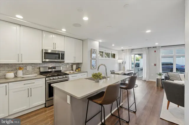 a kitchen with stainless steel appliances granite countertop a stove top oven a sink dishwasher a dining table and chairs with wooden floor