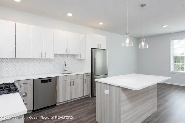 a kitchen with a sink a stove a refrigerator and white cabinets