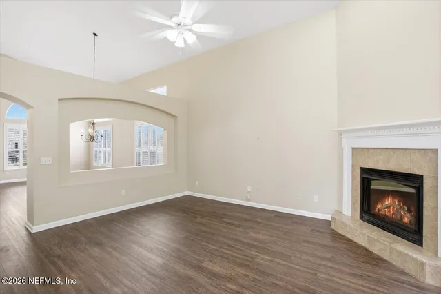 a view of an empty room with wooden floor fireplace and a window