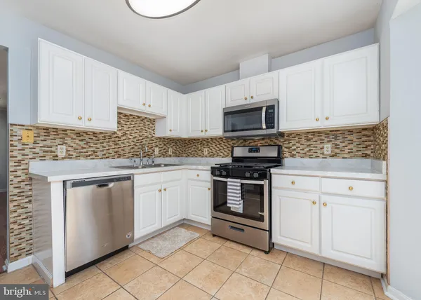 a kitchen with granite countertop white cabinets and stainless steel appliances